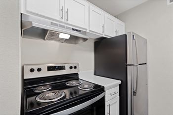 Kitchen with white cabinets and black appliances and a refrigerator